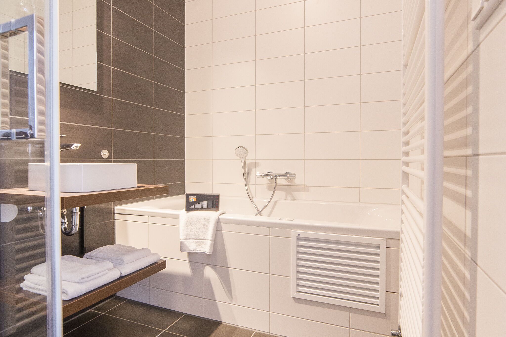 Un baño moderno con lavamanos blanco, bañera y ducha.