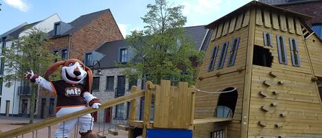 Un parque infantil con una estructura de madera para escalar y columpios.