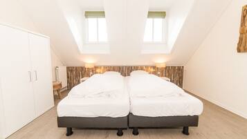 A bedroom with two beds, a wardrobe, a radiator, and a wooden wall panel.
