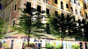 A multi-story hotel with a well-lit facade, large windows, and balconies. - Maison d'Rose (Phu Quoc)