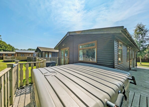 A wooden cabin with a deck, large windows, and a metal roof.