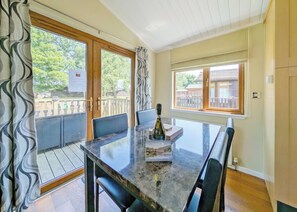 A dining area with a glass-top table, chairs, and a bottle of wine.