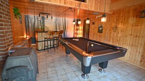 A pool table in a room with wooden walls and a brick accent wall. There is a bar area with stools and a stove. - Chalet in Beffe with Hot Tub & Valley Views (Beffe)