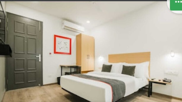 A modern hotel room with a large bed, a wardrobe, a desk, and an air conditioning unit. - The Town House (New Delhi)