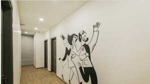 A hallway with a wall mural of stylized figures. - The Town House (New Delhi)