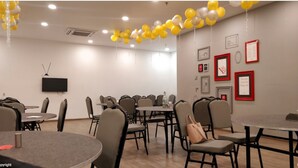 A conference room with round tables and chairs, a flat-screen TV, and framed artwork on the walls. - The Town House (New Delhi)