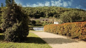 Un sentier menant à un bâtiment, avec une cascade en arrière-plan.