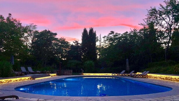 Une piscine avec des chaises longues et une terrasse en pierre.