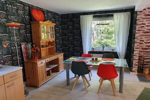 A dining area with a table, chairs, a cabinet, and a window with curtains.