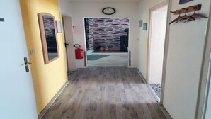 Käytävä, jossa on puulattia, seinällä oleva kello ja oikealla puolella ovi.