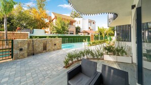 A patio with a pool, stone walls, and outdoor furniture.