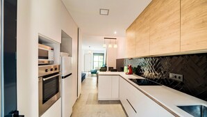 A modern kitchen with white cabinetry, stainless steel appliances, and a black backsplash.