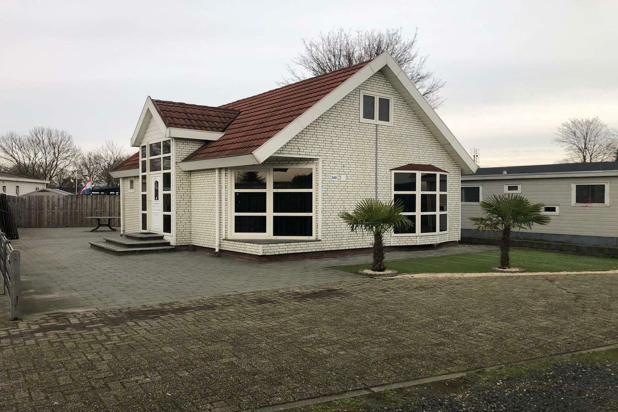 Einbungalow mit rotem Ziegeldach, weiß verputzter Fassade und großen Fenstern.
