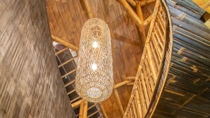 A spiral staircase with bamboo railings and a hanging light fixture. - Dreamy Cliffside Bamboo Villa with Pool and View (Klungkung)