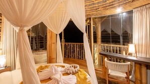 A room with a bed, a chair, a table, and a large window. - Dreamy Cliffside Bamboo Villa with Pool and View (Klungkung)