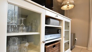 Un meuble vitré avec des étagères où sont rangés des objets en verre et un téléviseur à écran plat.