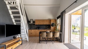 Een moderne keuken met een televisie, houten kastjes en een eethoek met stoelen.
