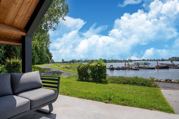 A modern outdoor seating area with a view of a lake and boats. - Beautiful house in Kerkdriel on the waterfront (Kerkdriel)