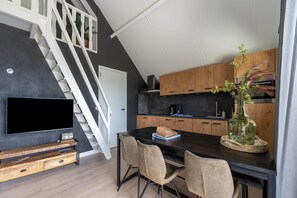 Une cuisine moderne avec un plan de travail noir, des meubles en bois et un escalier.