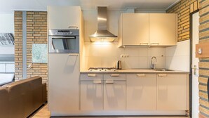 Een moderne keuken met een inbouwoven, een rvs afzuigkap en een gasfornuis.