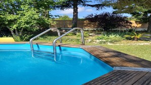 A swimming pool with metal ladders and a wooden deck.