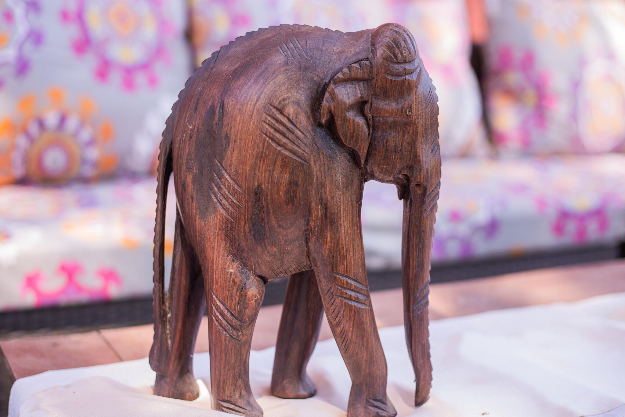 A wooden elephant sculpture on a white pedestal.