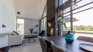 Ein modernes Wohnzimmer mit großem Esstisch, bequemen Sitzgelegenheiten und Ausblick durch große Fenster.