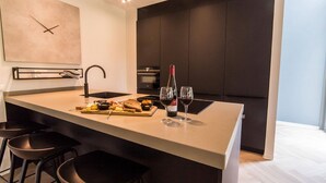 A modern kitchen with a central island, bar stools, a wine bottle, and glasses.