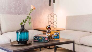 Ein modernes Wohnzimmer mit einer Couch, einem Couchtisch, einer Vase mit einer Blume, einem Spielzeug und einem Gesellschaftsspiel.