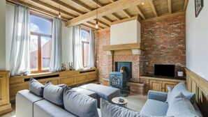 Una sala de estar acogedora con chimenea de ladrillo, vigas de madera y un ventanal con cortinas.