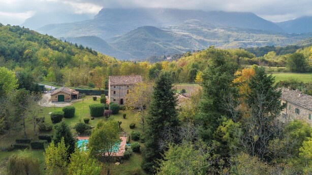 A rural landscape with a stone building surrounded by lush greenery and a swimming pool. - Large Group Retreat with Pool (Amandola)