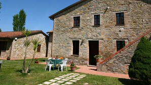 Un edificio de piedra con patio, mobiliario exterior y una escalera.
