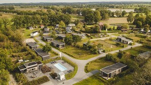 Ett flygbildsbild av ett bostadsområde med hus, en swimmingpool och grönområden.