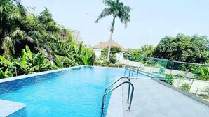 Une piscine à l’eau d’un bleu limpide, entourée d’une terrasse carrelée.
