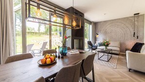 Un salon moderne avec un coin repas, de grandes fenêtres et une cheminée.