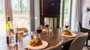 Une table à manger dressée avec des assiettes remplies de nourriture, des verres de vin et une bouteille de vin.