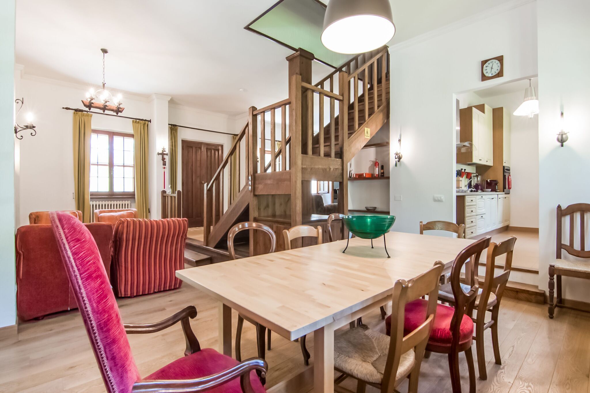 Ein Essbereich mit Holztisch und -stühlen, eine Treppe und eine Küche im Hintergrund.