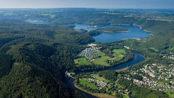 Luchtbeeld van een stad met een rivier, omringd door dichte bossen en heuvels.