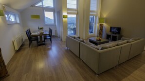 A modern living room with a dining area, large windows, and a television. - Modern penthouse with Rur valley view (Heimbach)