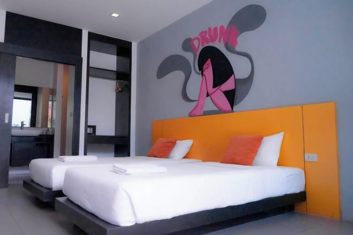 A hotel room with two beds, a large mirror, and a wall with a Mickey Mouse design.