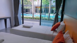A hotel room with two beds, a view of a swimming pool, and a dining area outside.
