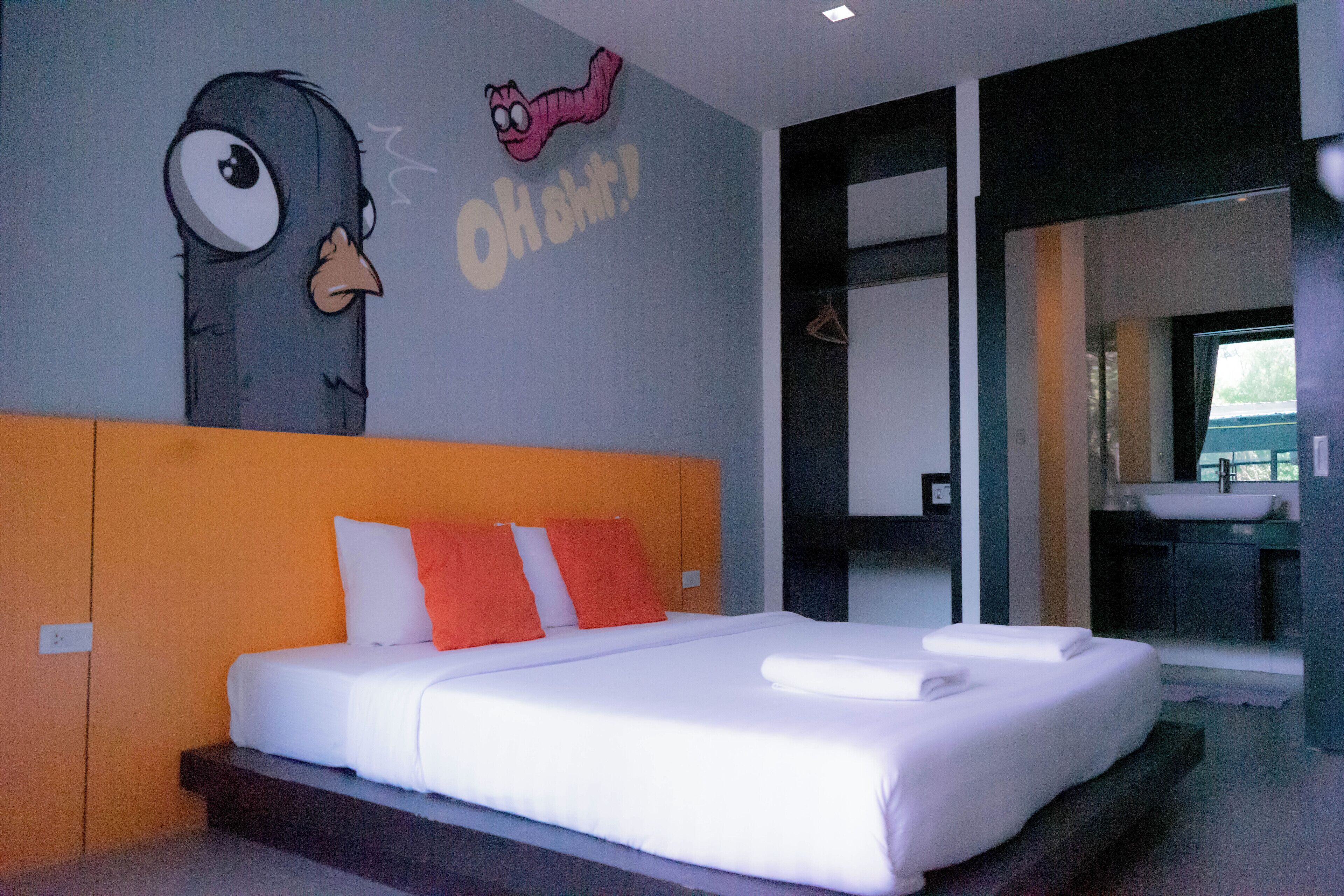 Un dormitorio moderno con una cama grande, cabecera naranja y un mural de un personaje de dibujos animados.