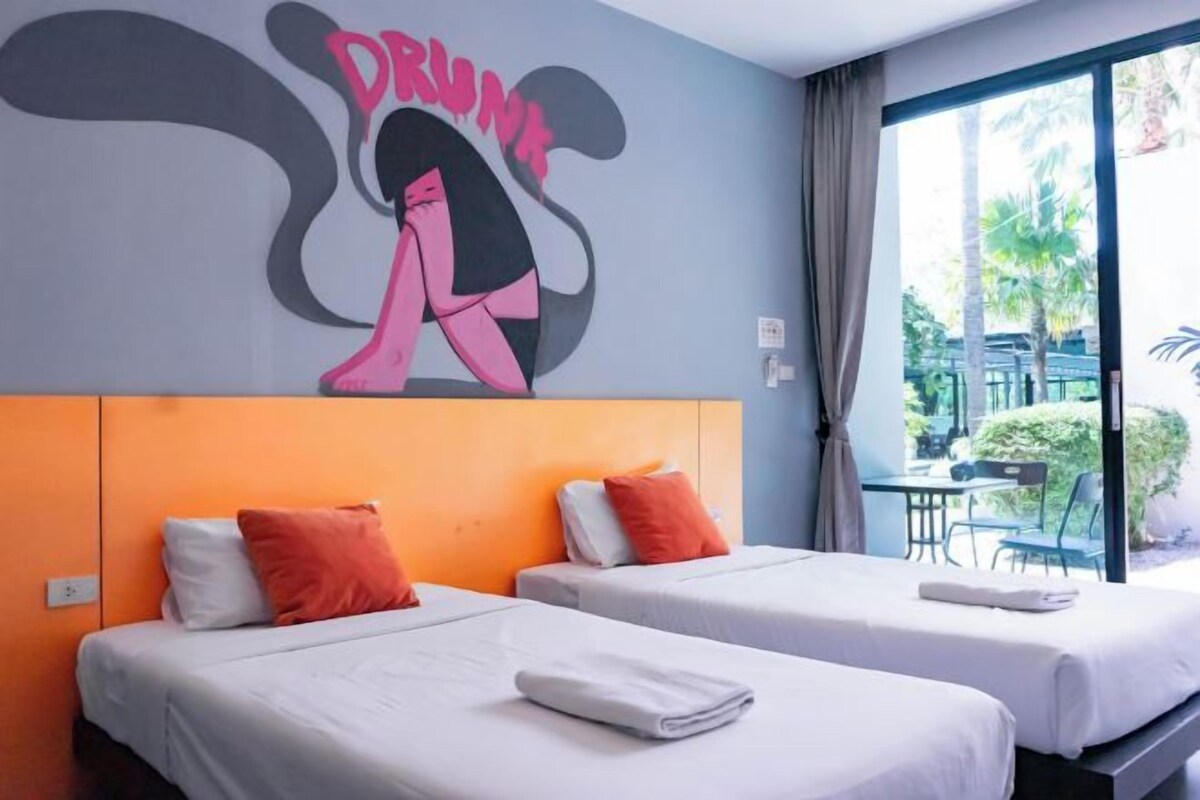 A hotel room with two beds, orange headboards, and a mural on the wall.