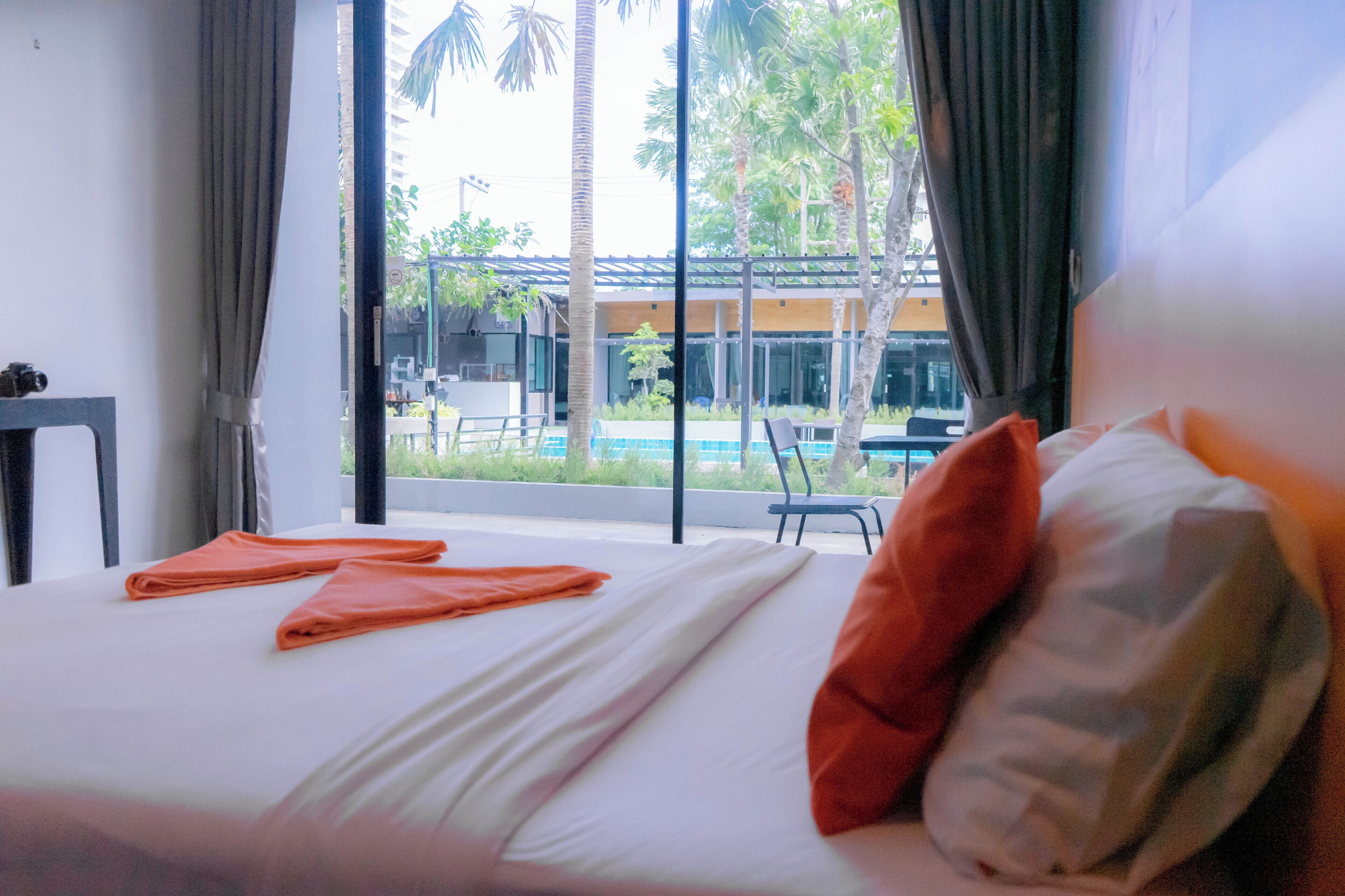 A hotel room with a bed, a view of a pool, and a table with a chair.