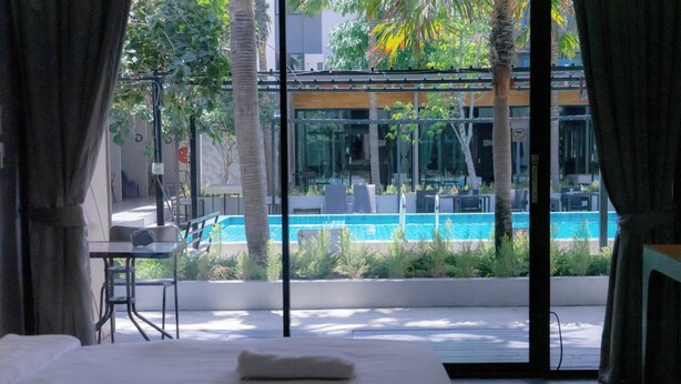 A hotel room with a bed, a desk, and a view of a swimming pool.
