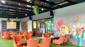 A conference room with orange chairs and a large table, a green artificial turf floor, and a mural with a cartoon character on the wall.