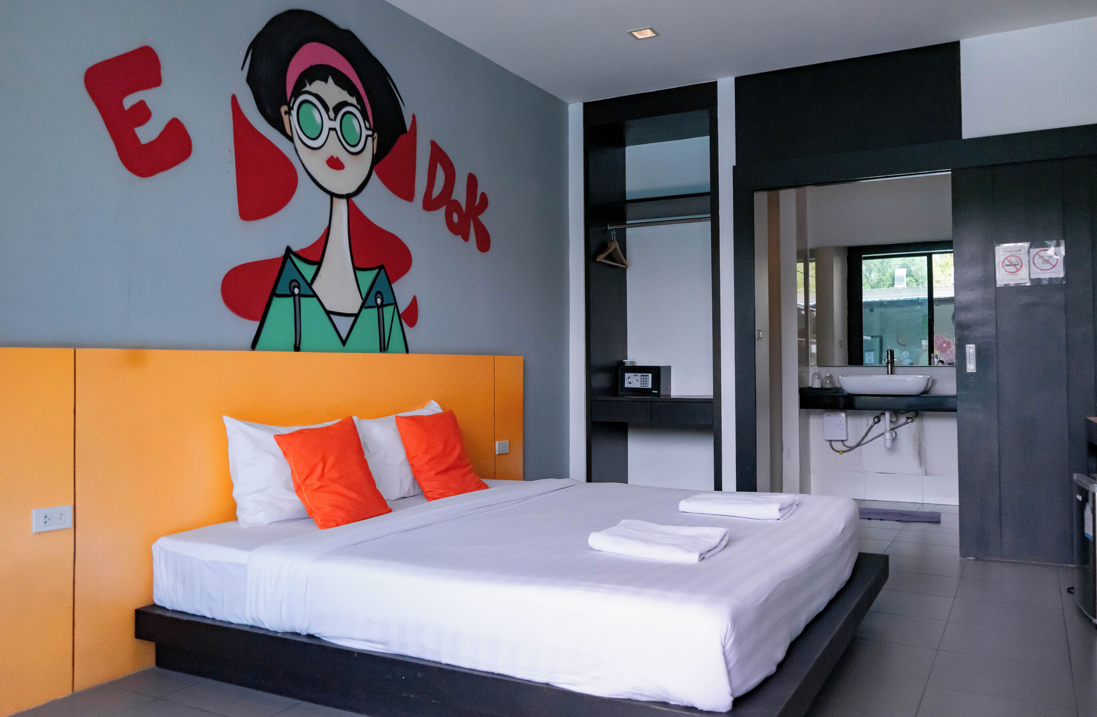 Habitació d'hotel moderna amb un llit gran, amb melenari taronja i un mural a la paret.