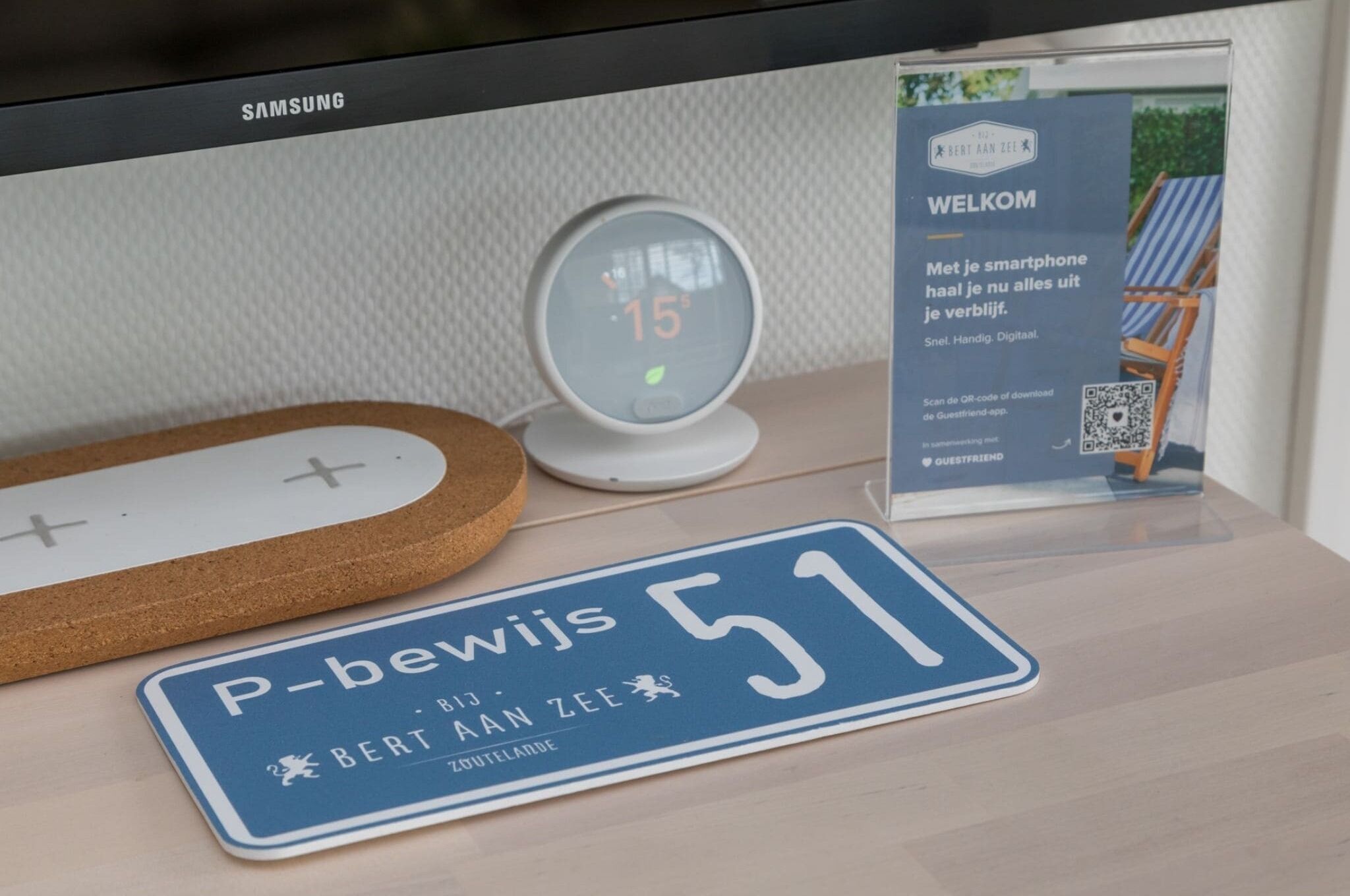 Un monitor Samsung mostra un messaggio di benvenuto, un orologio digitale e un codice QR per un'app per gli ospiti.