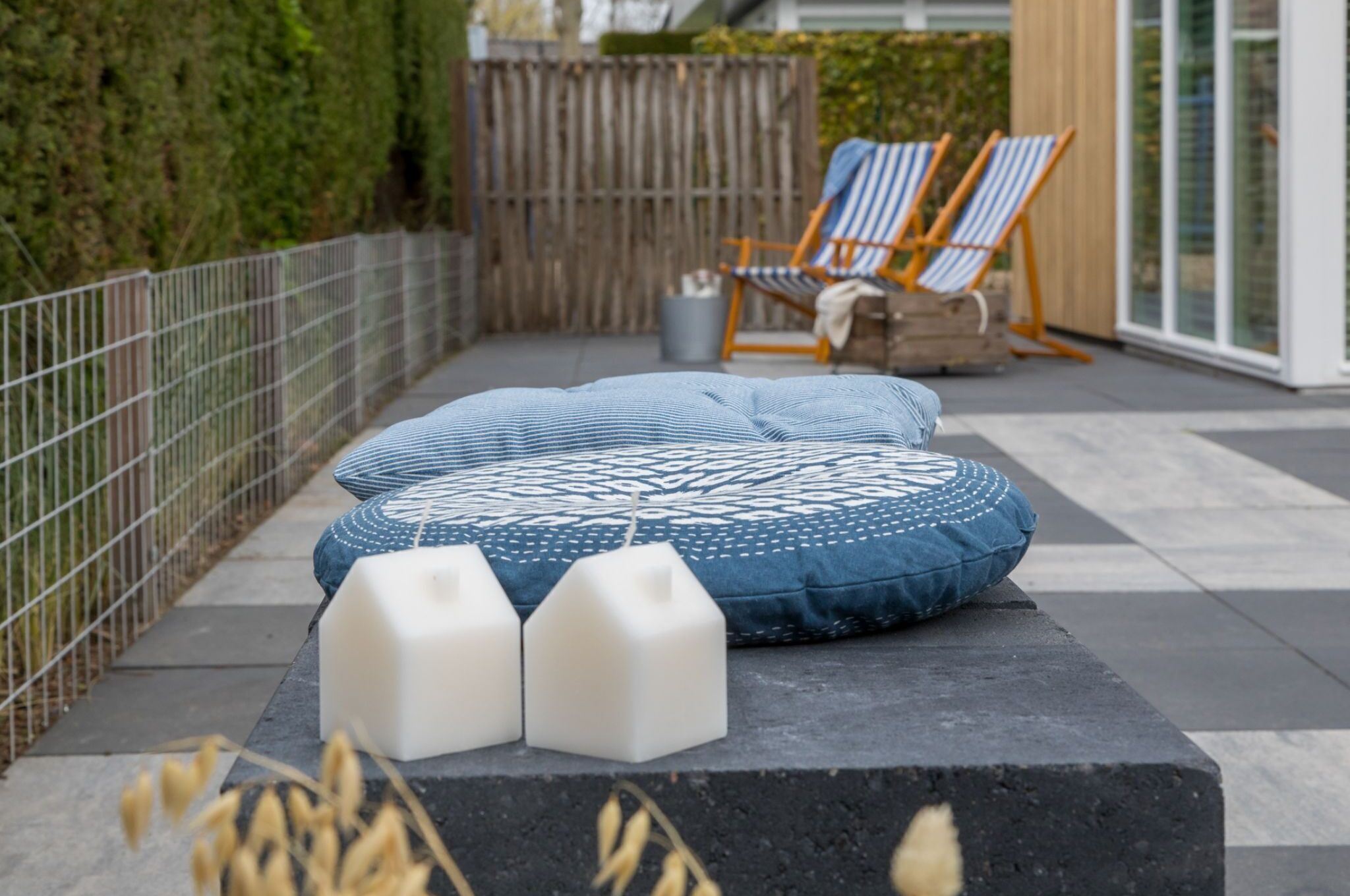 A patio area with a patterned cushion, two white blocks, and striped chairs.