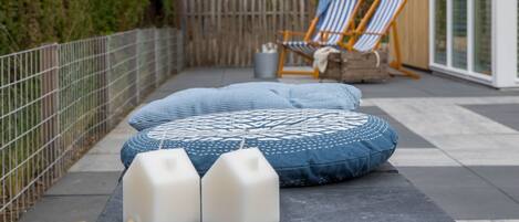 A patio area with a patterned cushion, two white blocks, and striped chairs.